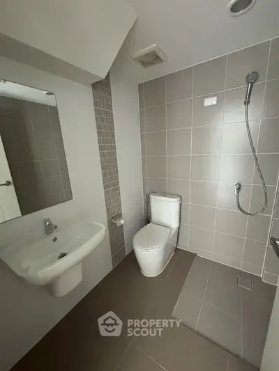 Modern bathroom with sleek tiles and shower area in contemporary apartment.