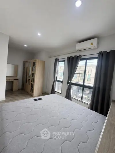 Spacious bedroom with large windows and modern furnishings in a stylish apartment.