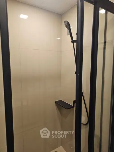 Modern shower area with sleek black fixtures and glass enclosure in a contemporary bathroom.