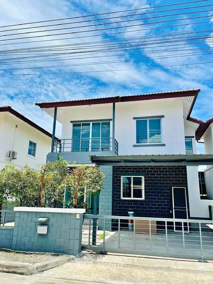 Modern two-story house with balcony and sleek exterior design under a clear blue sky.