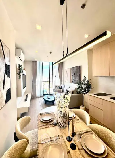 Modern open-plan living room with dining area, stylish decor, and large windows offering natural light.