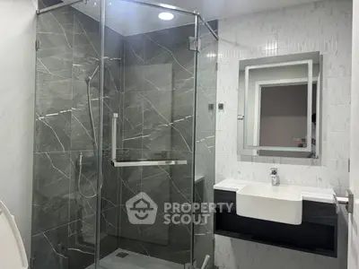 Modern bathroom with glass shower and sleek vanity in luxury apartment.