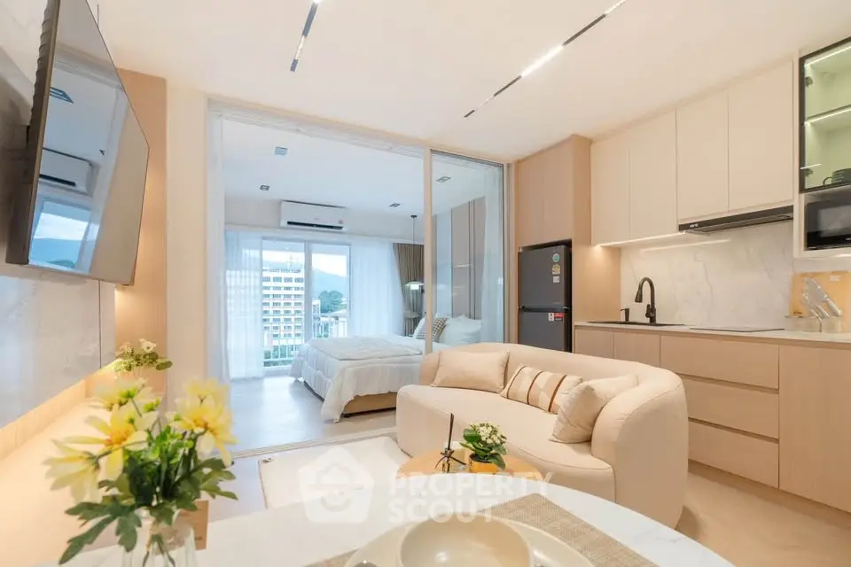 Modern open-plan living room and kitchen with cozy bedroom view