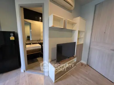 Modern apartment interior with sleek TV unit and bathroom view, featuring contemporary design and efficient use of space.