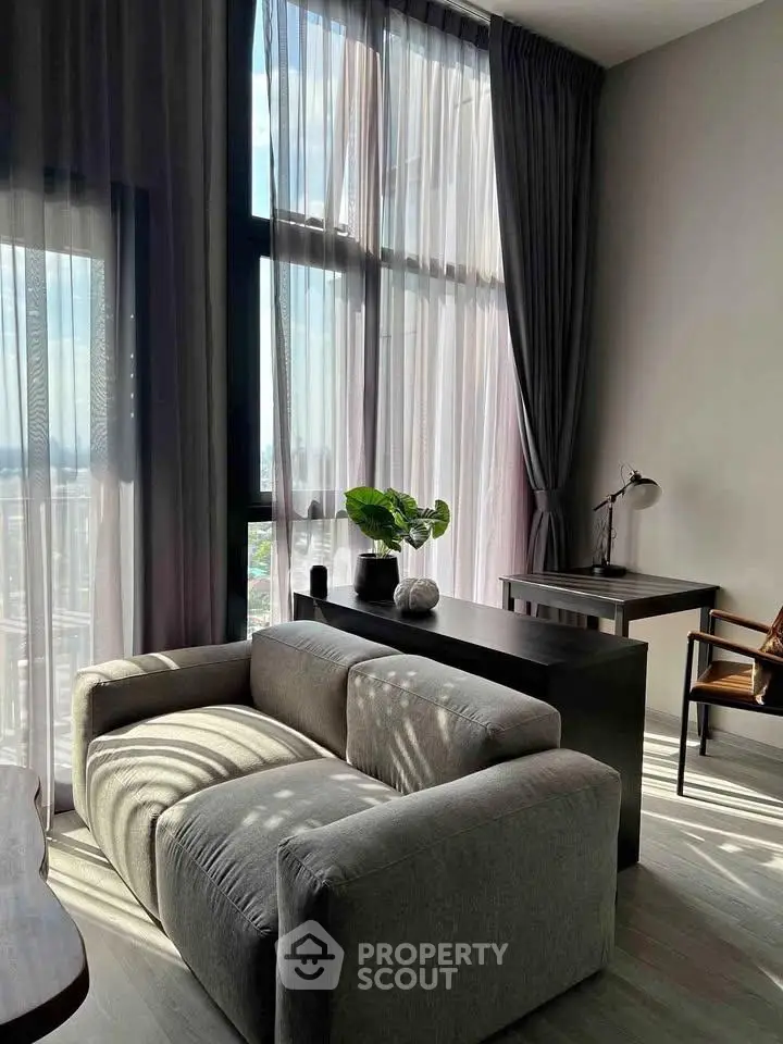 Modern living room with large windows, stylish furniture, and abundant natural light.