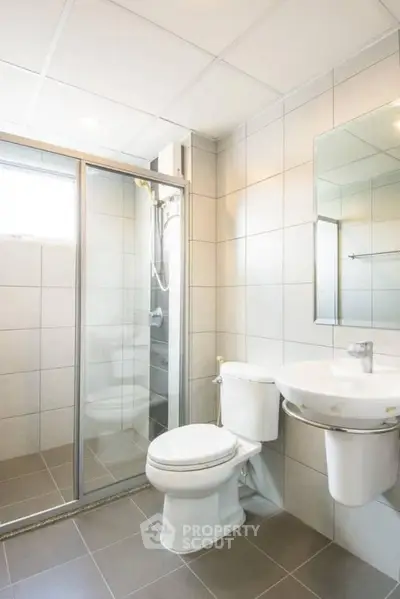 Modern bathroom with glass shower and sleek fixtures in a bright, tiled space.