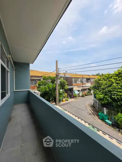 Charming balcony view of suburban neighborhood with lush greenery and clear skies.