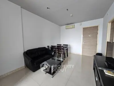 Modern living room with sleek black sofa, glass coffee table, and dining set in a minimalist apartment.