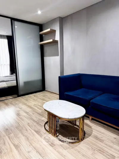 Modern living room with blue sofa and marble coffee table, featuring wooden flooring and sliding glass door.
