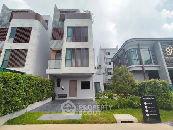 Modern luxury townhouse with sleek design and lush greenery in upscale neighborhood.