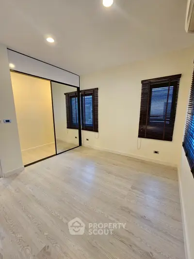 Spacious bedroom with wooden flooring and mirrored closet doors