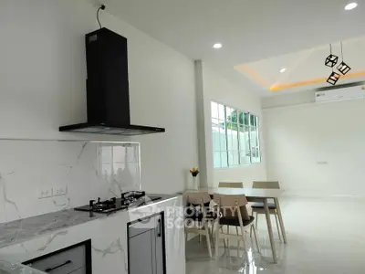 Modern kitchen with open layout and dining area, featuring sleek design and natural light.