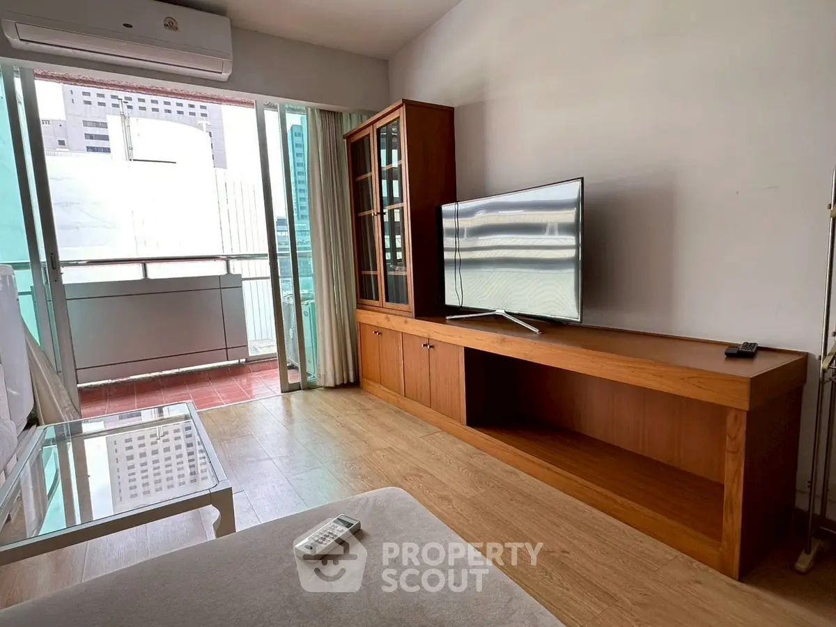 Modern living room with balcony view, featuring sleek TV unit and air conditioning.