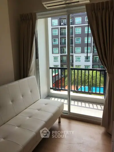 Modern apartment with balcony view overlooking pool and neighboring building.