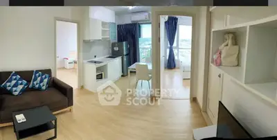 Modern open-plan living room with kitchen and city view, featuring stylish decor and ample natural light.