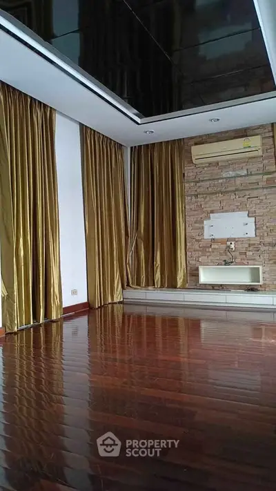 Spacious room with wooden floors and elegant curtains, ideal for modern living.