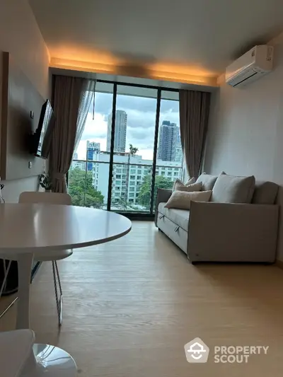 Modern living room with city view, cozy sofa, and wall-mounted TV in a stylish apartment.