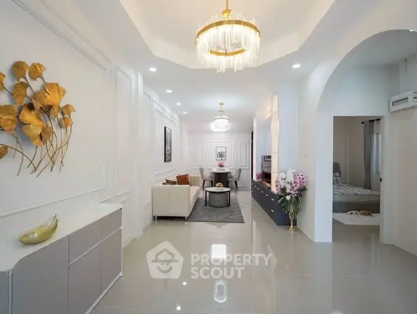 Elegant living room with modern decor and chandelier lighting, featuring a cozy seating area and stylish wall art.
