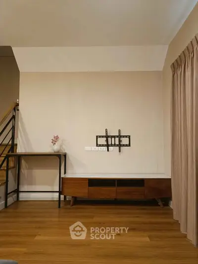 Modern living room with wooden flooring and TV mount, ideal for cozy gatherings.