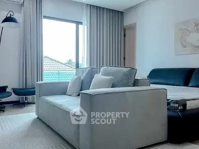 Modern living room with stylish sofa and large window offering natural light.