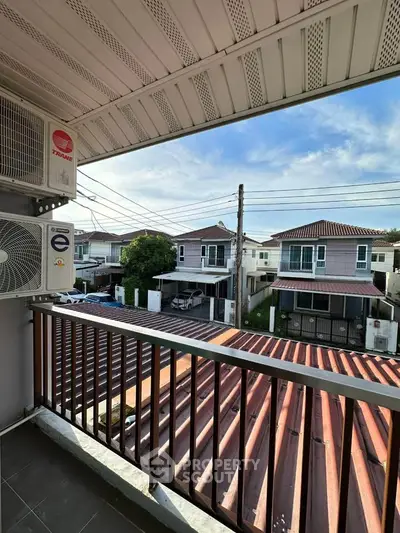 Charming balcony view overlooking suburban neighborhood with modern houses and clear blue sky.