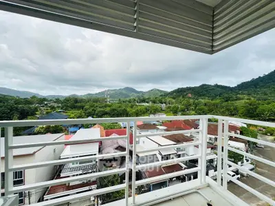 Stunning balcony view overlooking lush green hills and residential area.