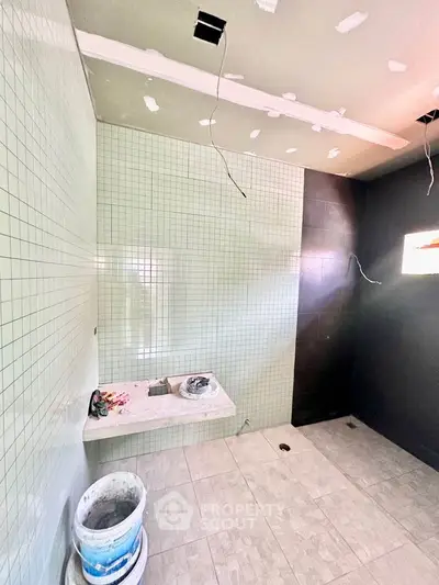 Modern bathroom under renovation with tiled walls and floor, featuring a sleek design.