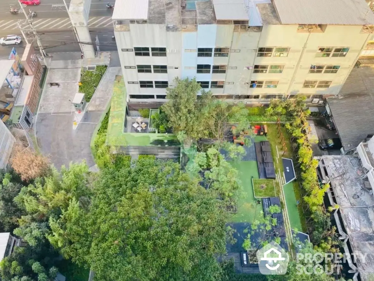 Aerial view of urban residential building with lush green garden and outdoor seating area.