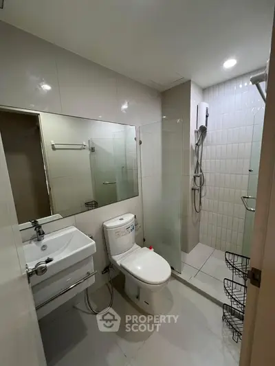 Modern bathroom with sleek fixtures and glass shower enclosure in contemporary apartment.
