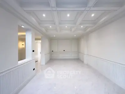 Spacious and elegant living room with coffered ceiling and marble flooring