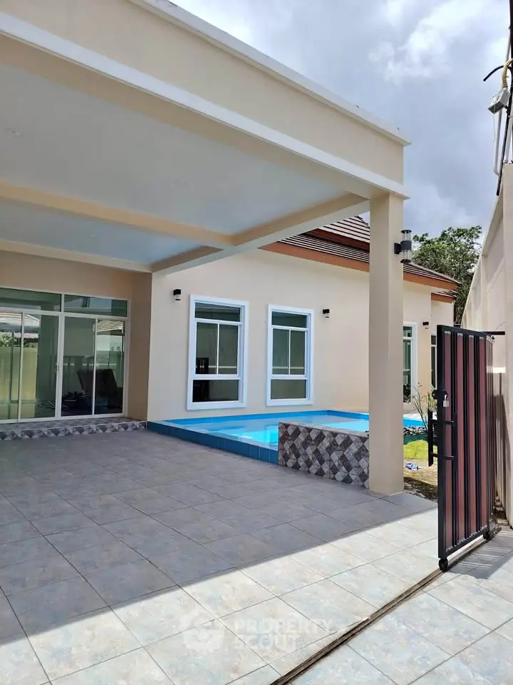 Modern home exterior with pool and spacious tiled patio area.