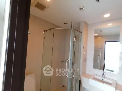 Modern bathroom with glass shower and sleek fixtures in a contemporary apartment.