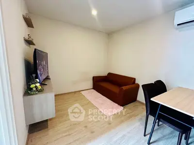 Cozy living room with modern decor, featuring a comfortable sofa, wall-mounted TV, and dining area.