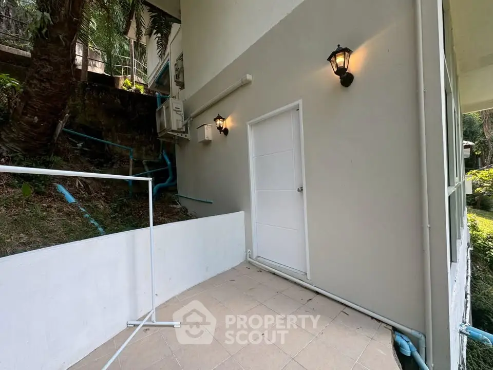 Charming exterior view of a modern building entrance with outdoor lighting and lush greenery.