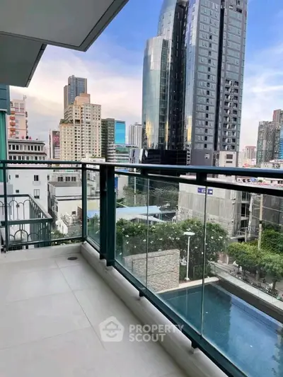 Stunning city view from modern balcony overlooking urban skyline and pool.