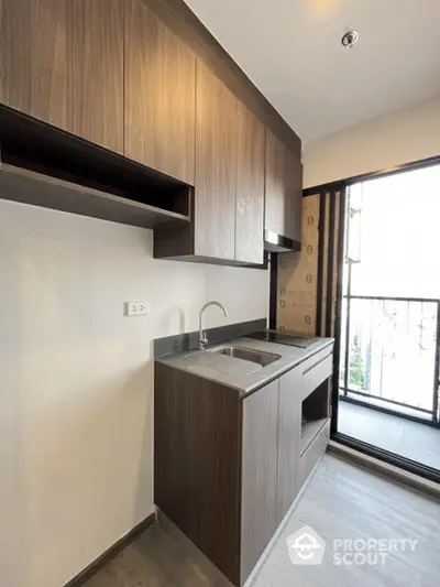 Modern kitchen with sleek wooden cabinets and balcony view