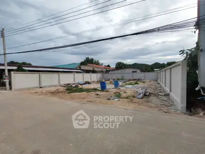 Vacant land plot with boundary walls in a residential area, ideal for new construction projects.