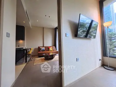 Modern living room with wall-mounted TV and cozy seating area in a stylish apartment.