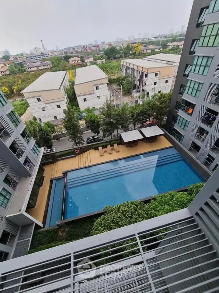 Stunning aerial view of modern apartment complex with luxurious swimming pool and lush greenery.