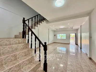 Spacious tiled living area with elegant staircase and natural light