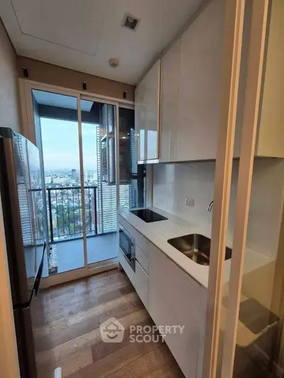 Modern kitchen with sleek design and balcony view in high-rise apartment