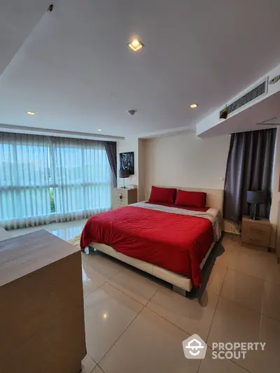 Spacious bedroom with modern decor and large windows offering natural light.