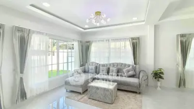 Elegant living room with plush gray sofa and modern chandelier in bright airy space.