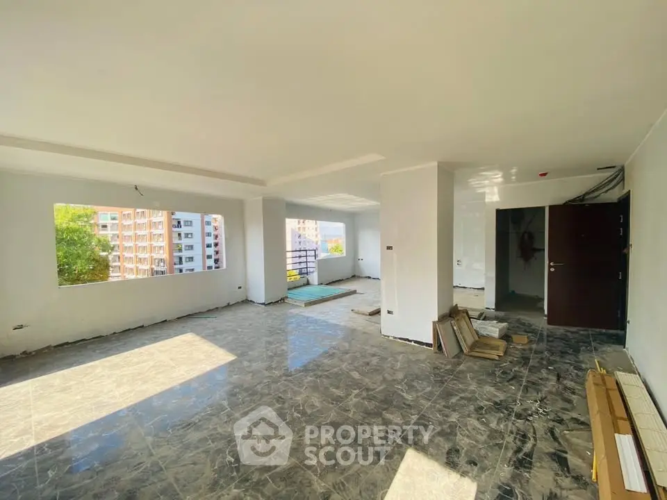 Spacious open-plan living area with large windows and marble flooring in a modern apartment.