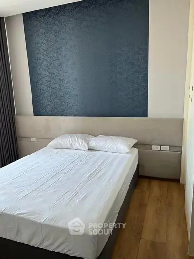 Modern bedroom with stylish accent wall and wooden flooring, perfect for a cozy retreat.