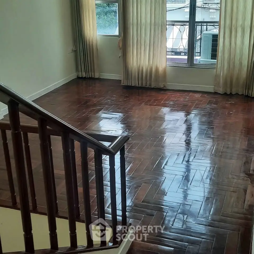 Spacious living room with polished wooden floors and large windows for natural light.