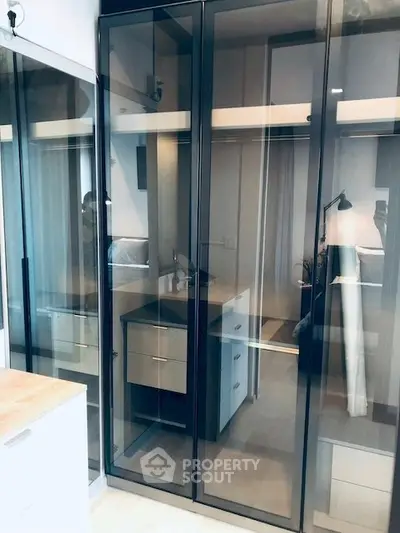 Modern bedroom with sleek glass wardrobe and stylish interior design.