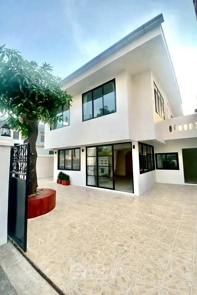Modern two-story white house with large windows and spacious tiled patio.