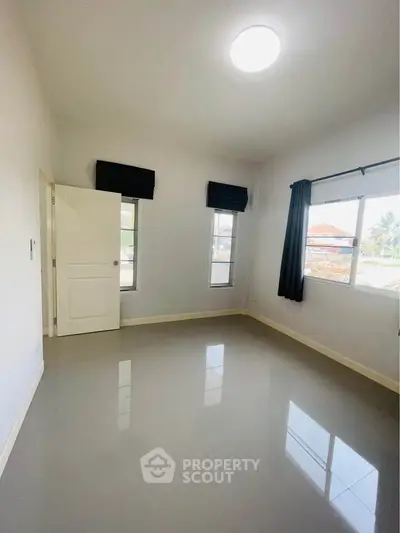 Spacious empty bedroom with glossy tiled floors and large windows