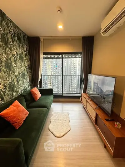 Stylish living room with green sofa, large window, and city view in modern apartment.